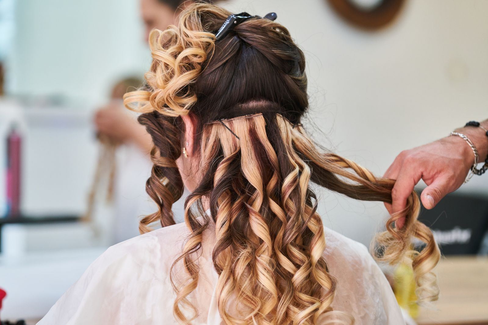 Stylist curling long blonde hair into soft waves