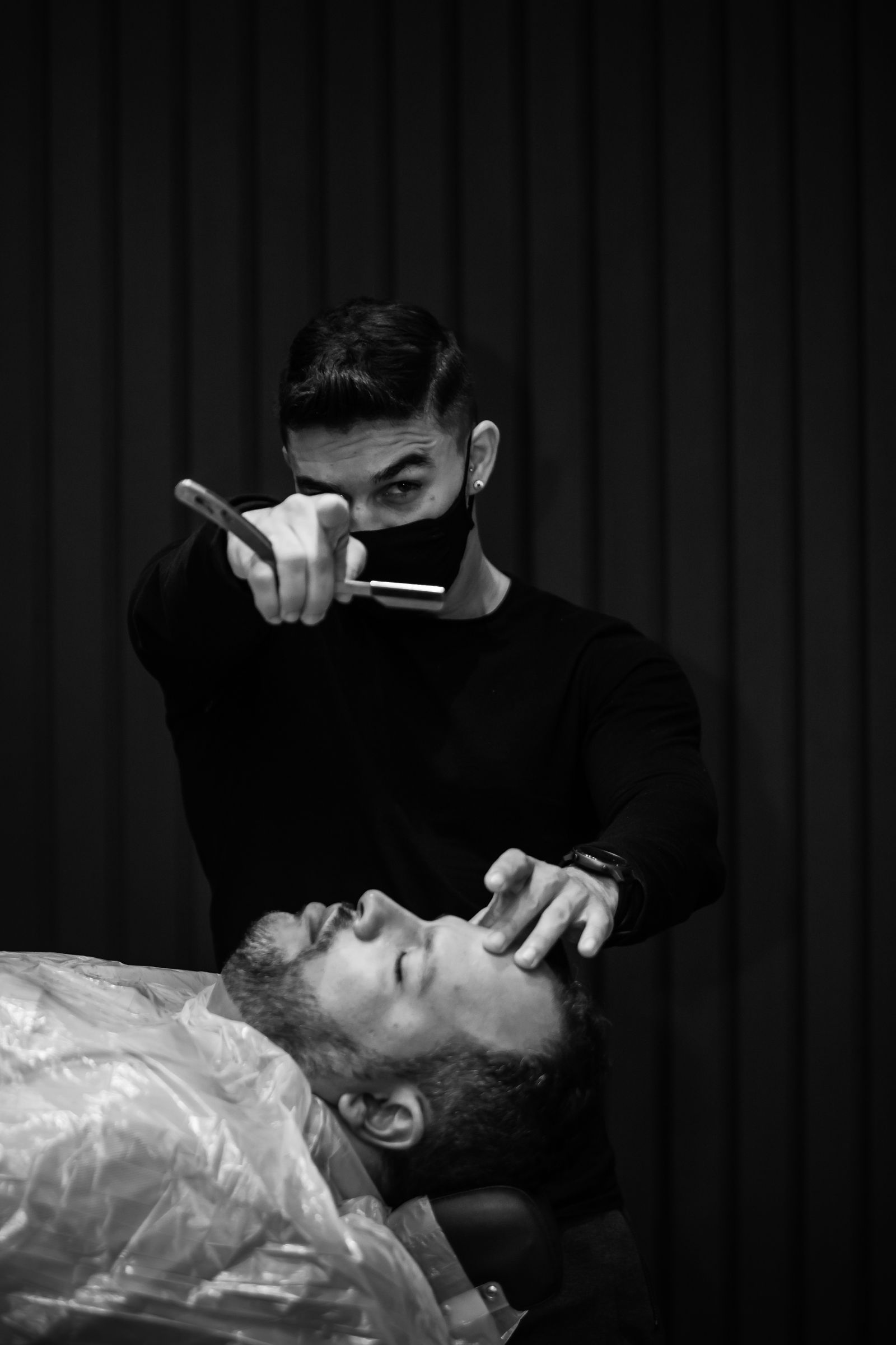 Barber performing a straight-razor shave on a reclined client