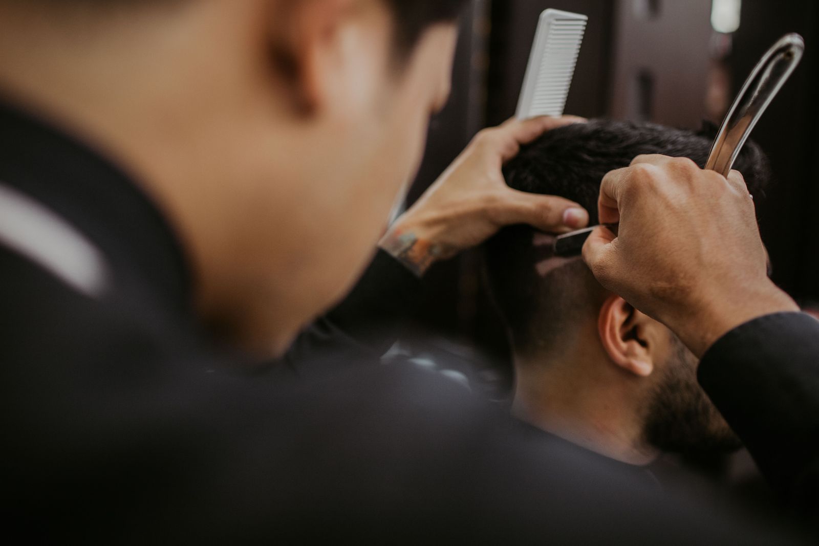 Barber tracing a crisp neckline with a straight razor and comb