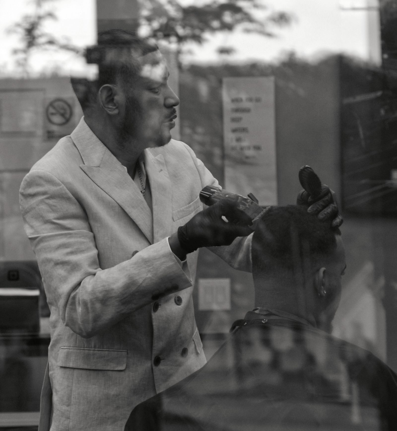 Black-and-white photo of a barber in a tailored suit at work
