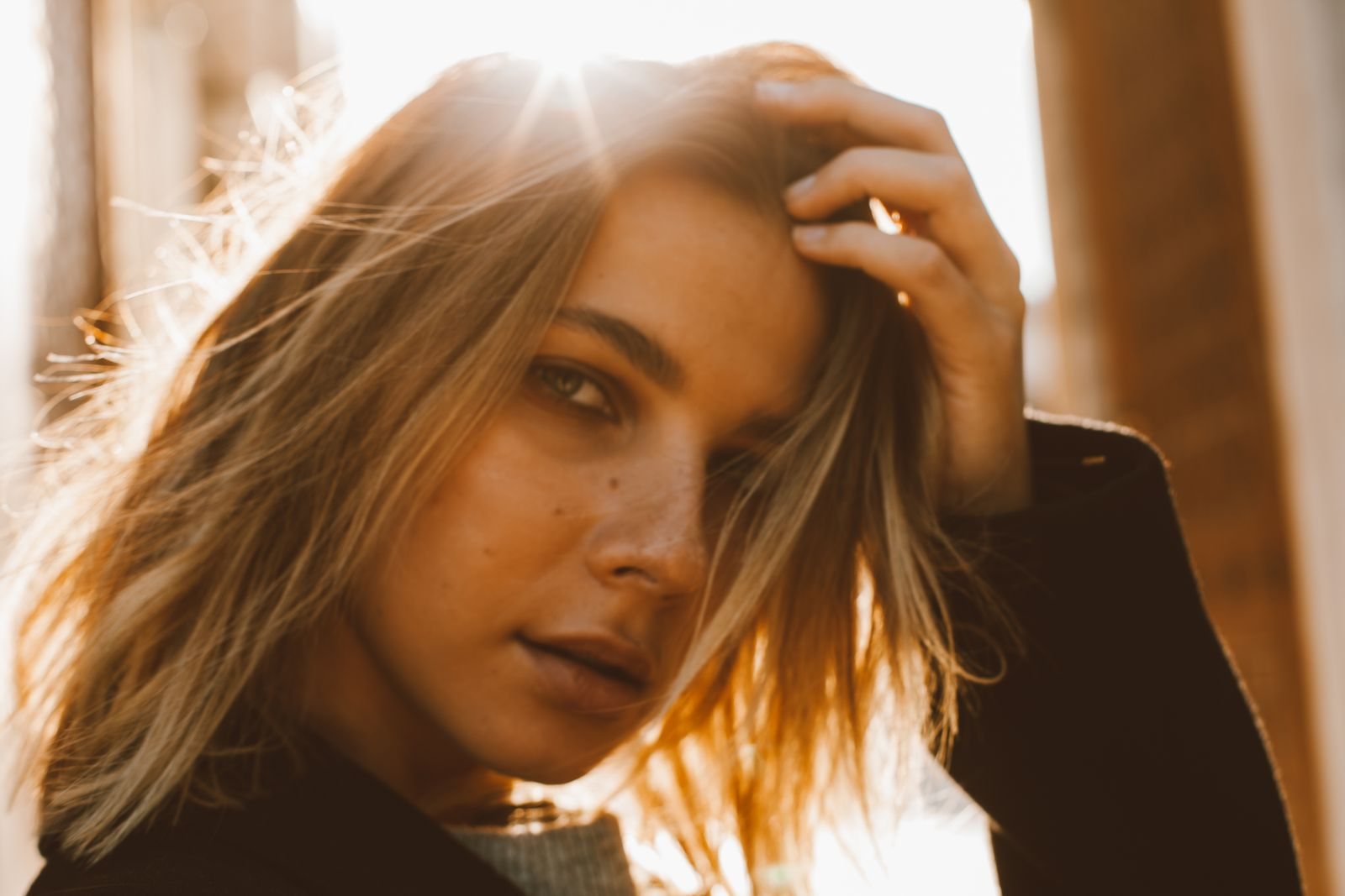 Woman with sunlit golden-blonde hair glowing in evening window light
