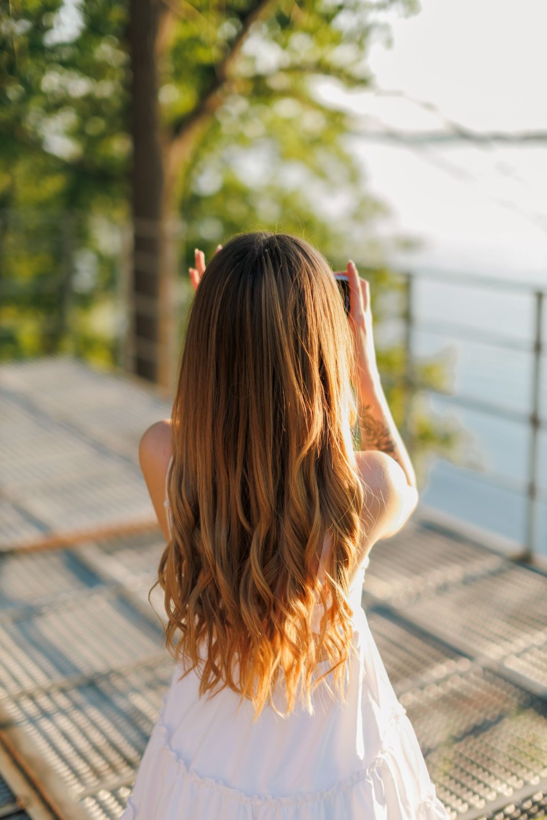 Long caramel-to-honey balayage on a sunny balcony