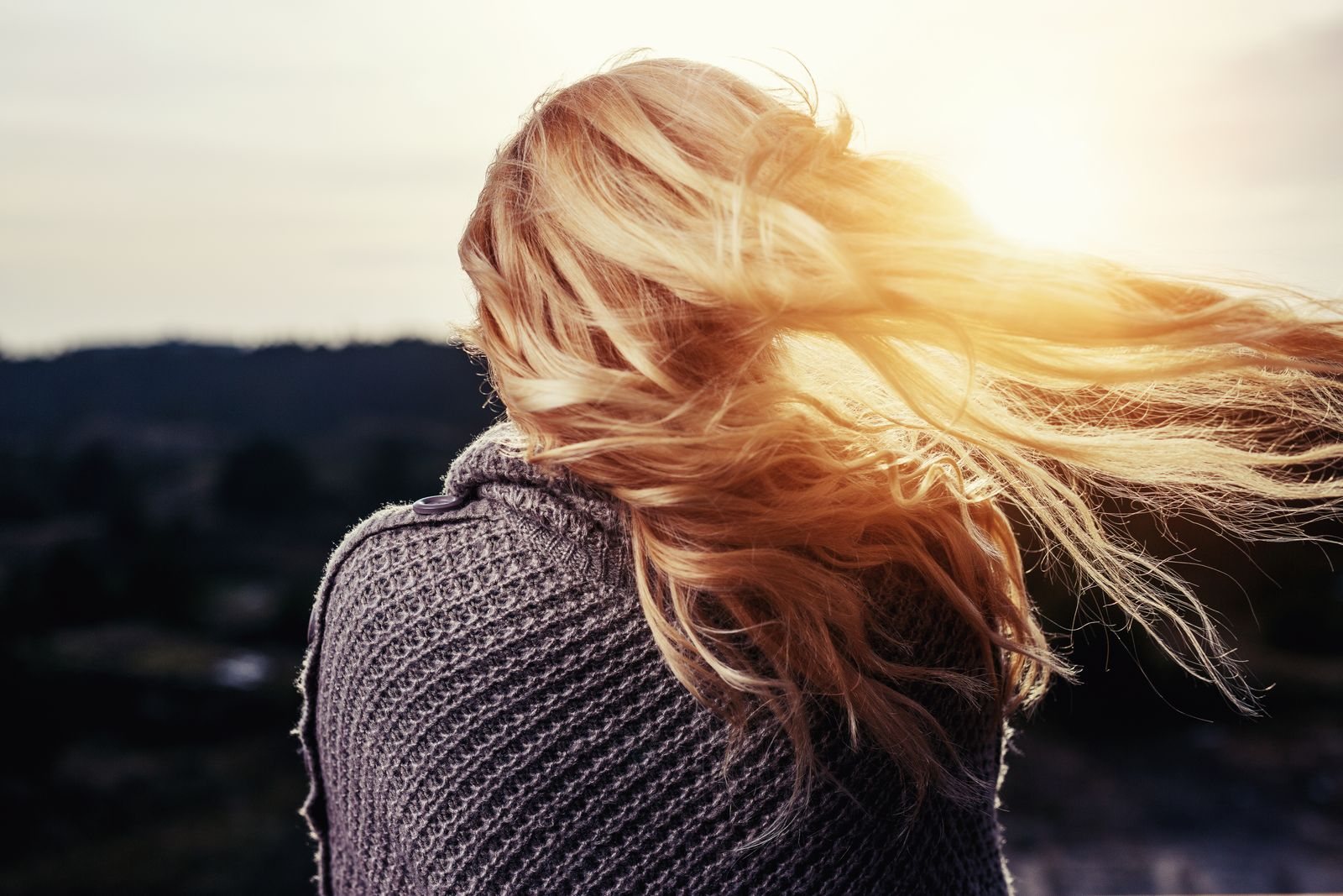 Long honey-blonde balayage catching golden-hour sunlight as it blows in the wind