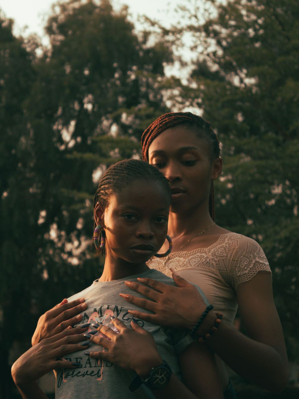 Two women with natural curly hair embracing at golden hour