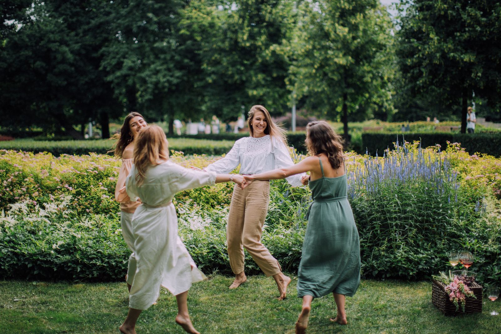 Bride and bridesmaids dancing in a circle in a garden