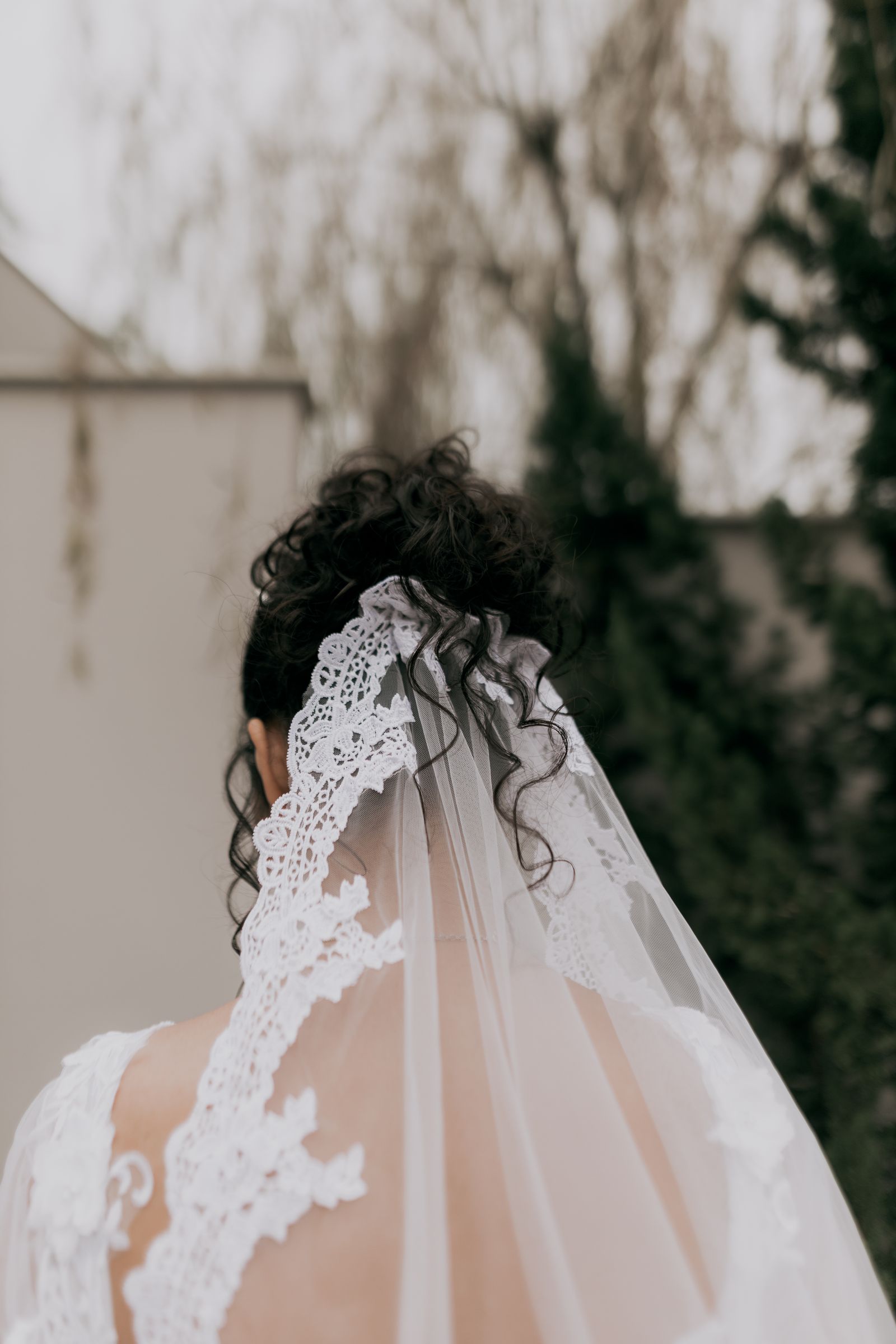 Soft pinned bridal curls under a lace-edged cathedral veil