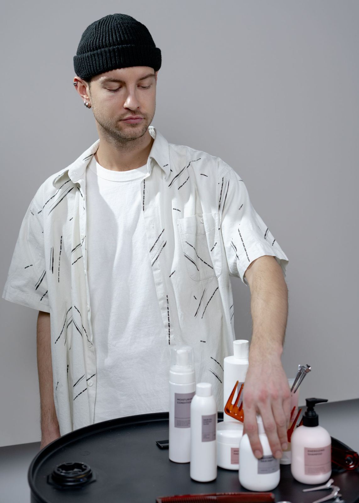 Barber in a beanie arranging grooming products