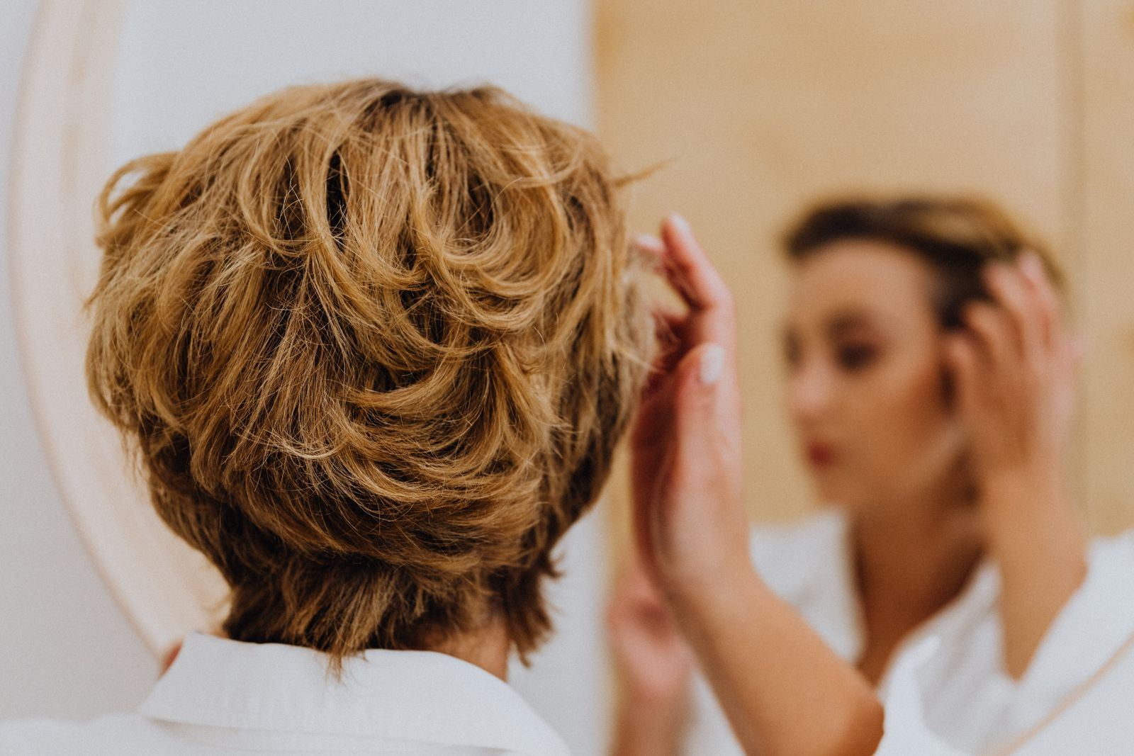 Short tousled curls checked in the mirror