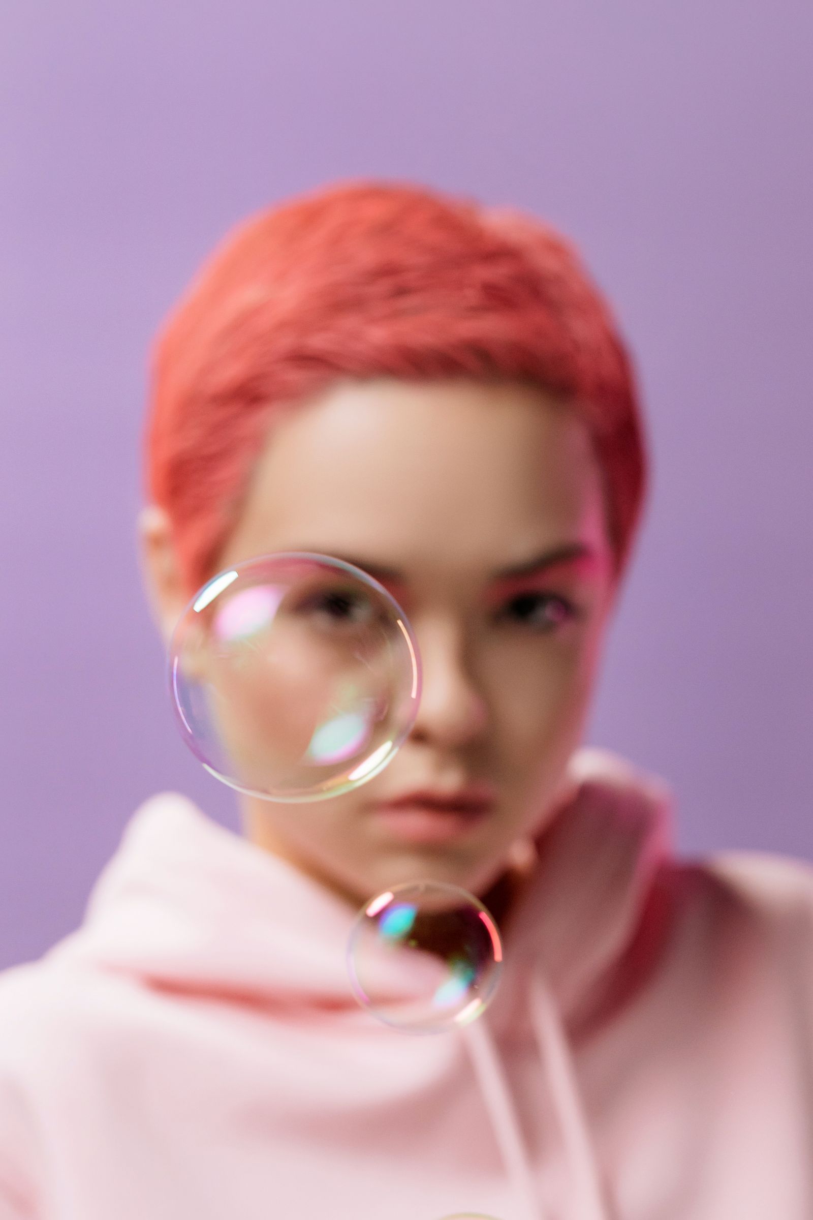 Person with a coral pixie cut and soap bubbles