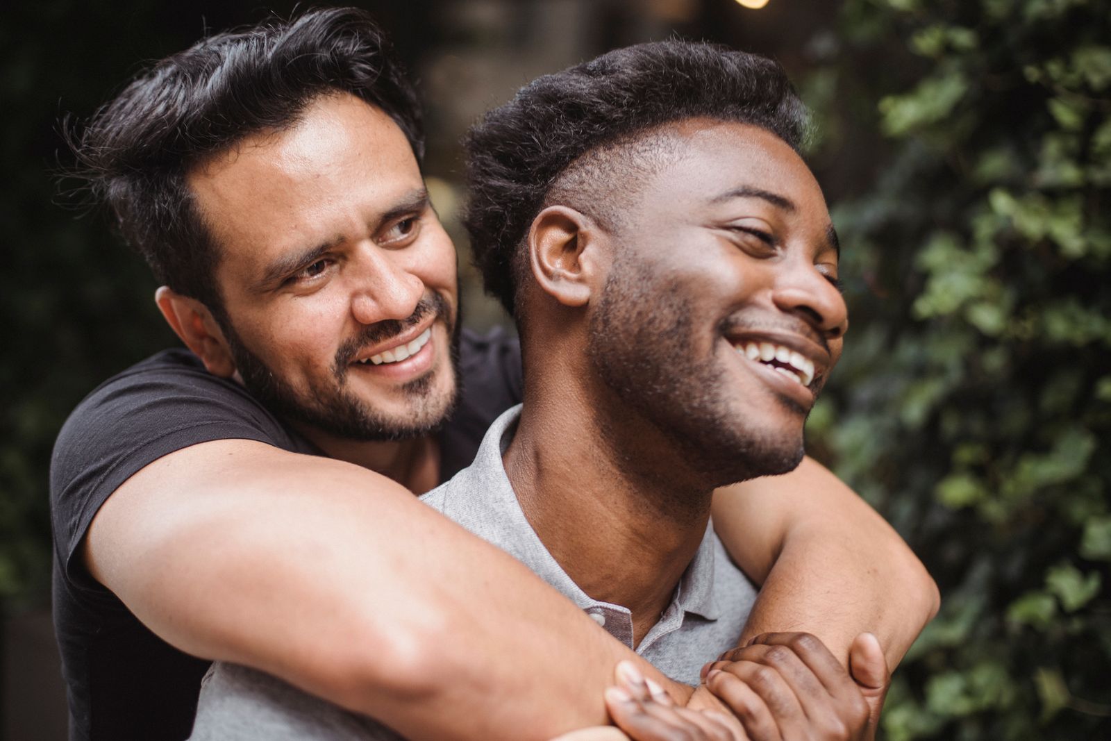 Two men laughing and hugging outdoors