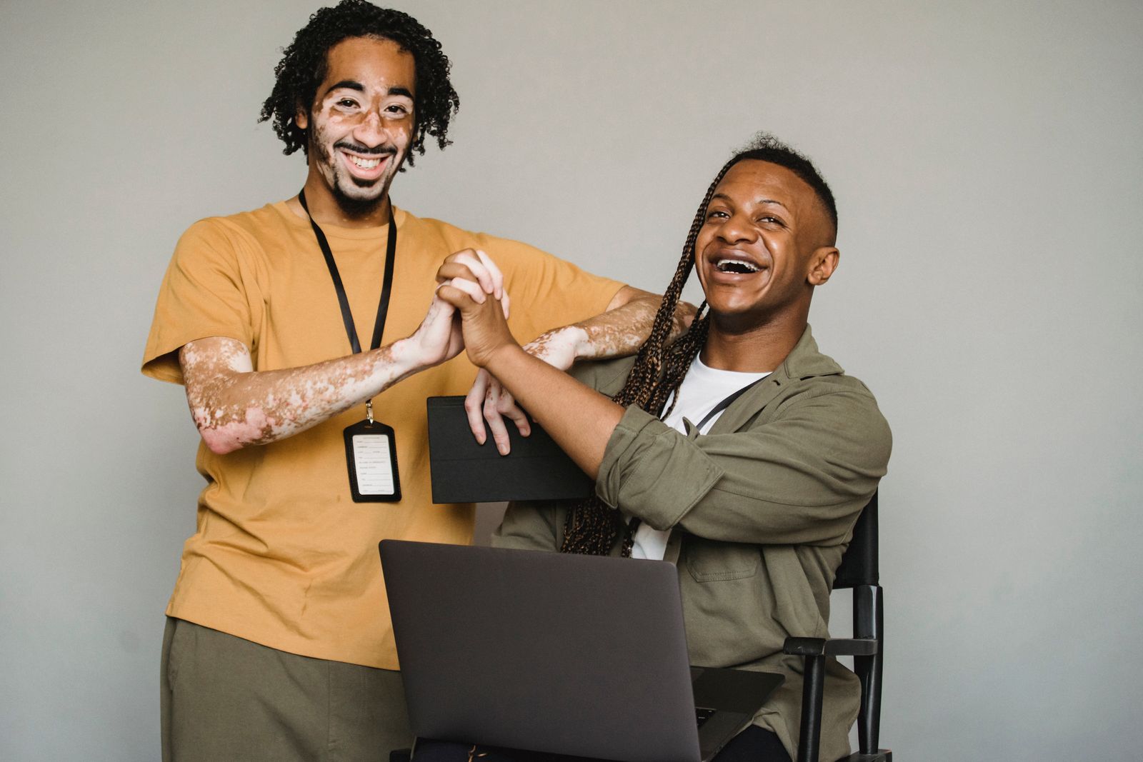 Two friends laughing together, one in a mustard shirt, one with long braids