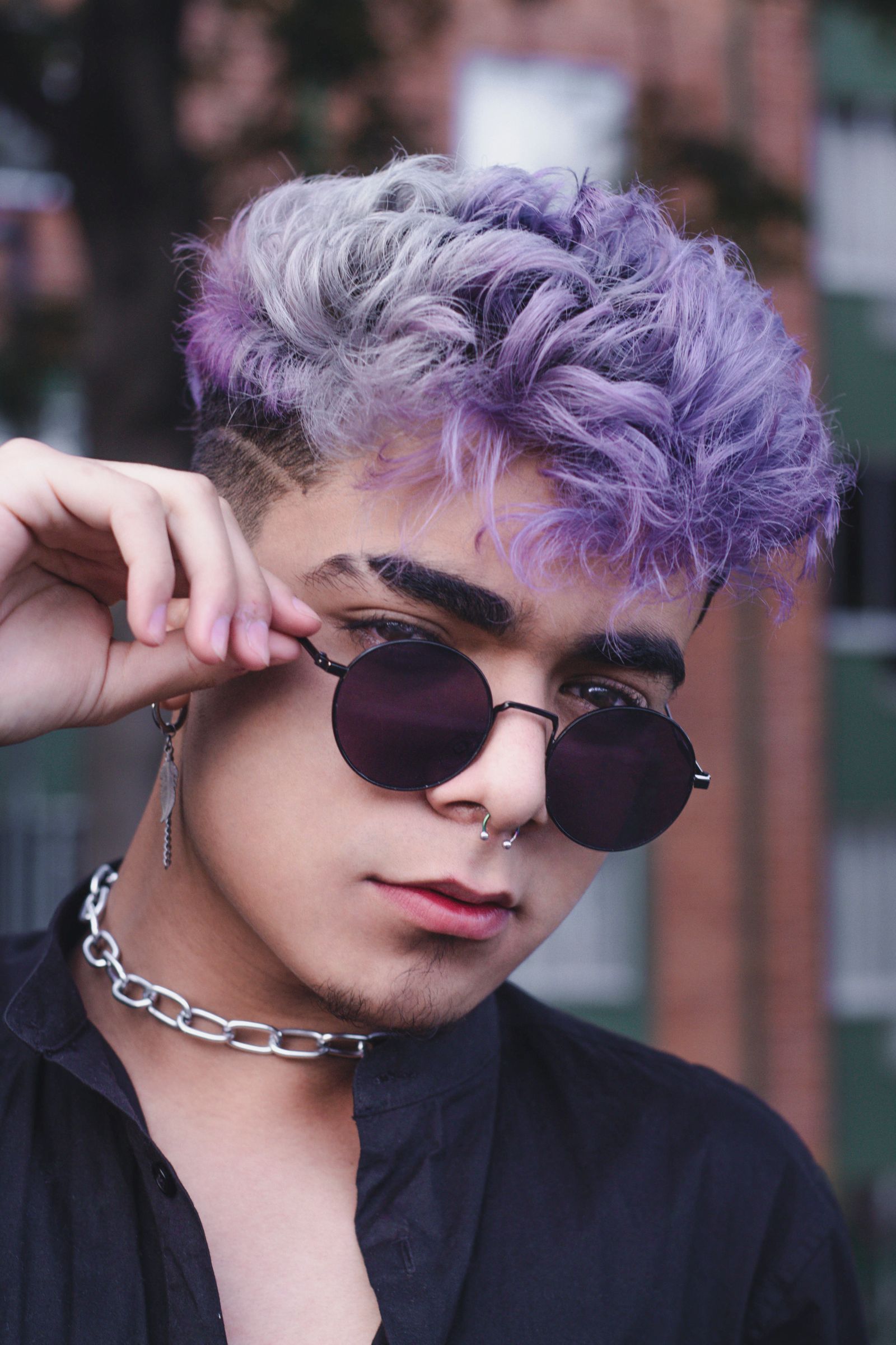 Person with lilac and silver curls and round sunglasses