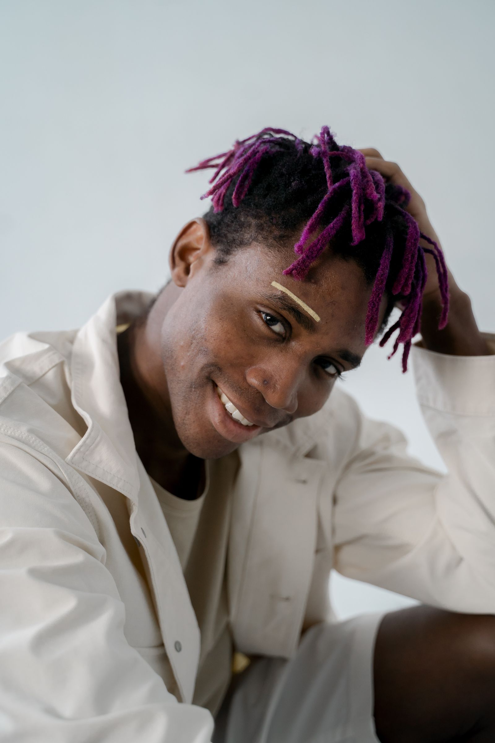 Smiling man with magenta-tipped locs