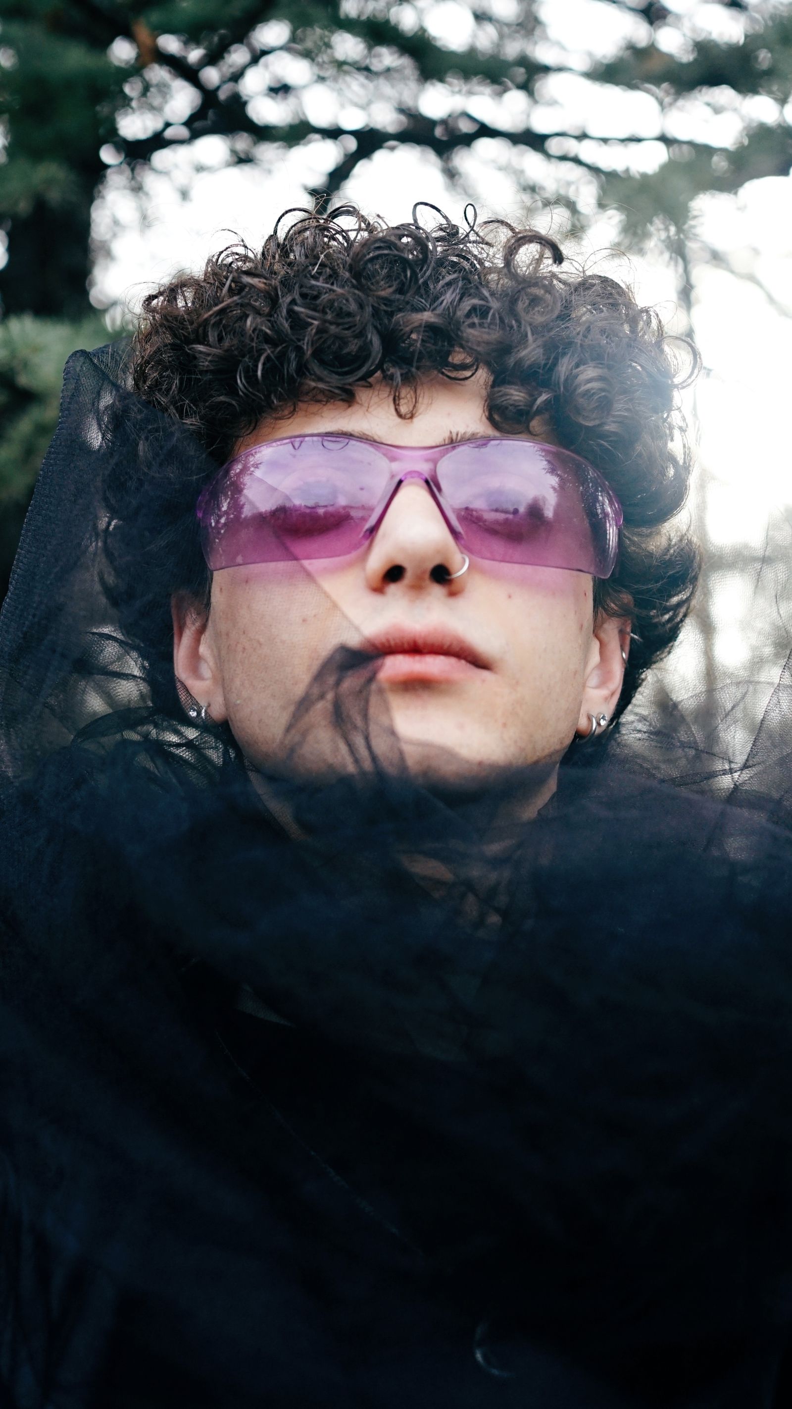 Person with curly hair and pink-tinted sunglasses