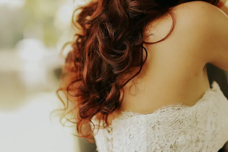 Close-up shot of a woman with wavy hair wearing a white lace top, showcasing texture and style.