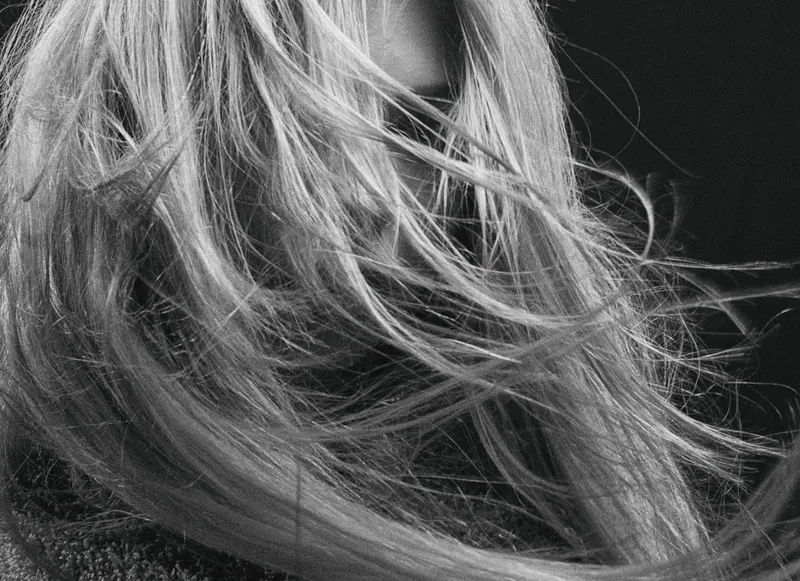 Artistic black and white close-up of a person with wind-swept hair, conveying mystery and elegance.