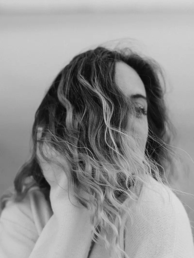 Elegant black and white portrait of a woman with flowing wavy hair. Calm and introspective mood.
