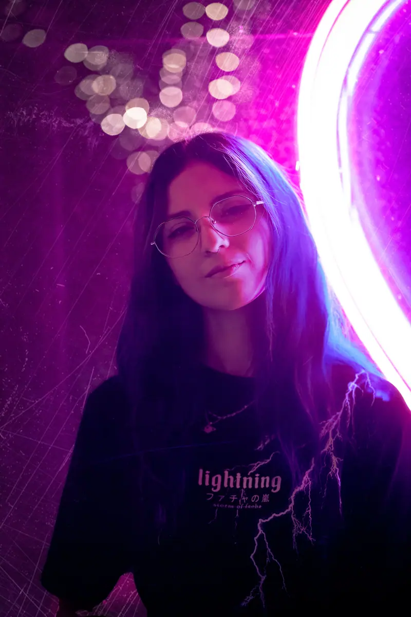 Stylish portrait of a woman in neon lighting with eyeglasses and long hair, exuding a modern and artistic vibe.