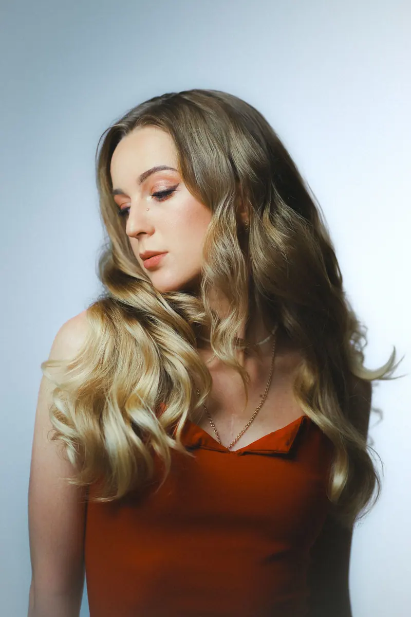 Elegant portrait of a blonde woman in a studio shot wearing a red dress.