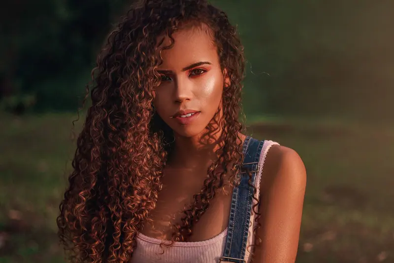 Vibrant portrait of a woman with curly hair in a sunlit park, capturing the essence of summer.
