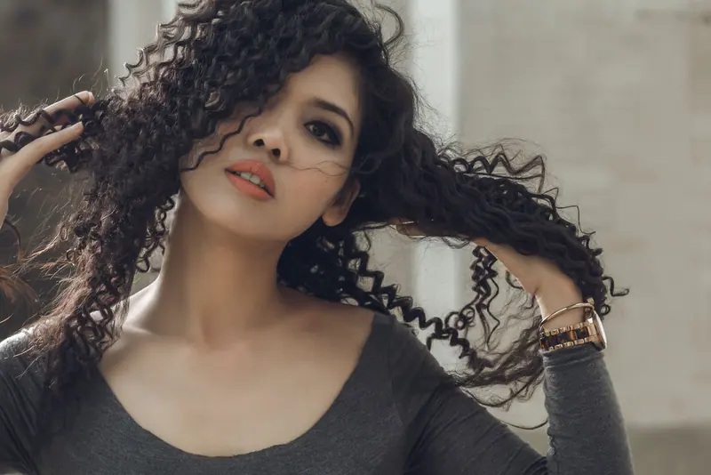 Stylish woman with curly hair in an elegant pose, showcasing confidence and beauty.