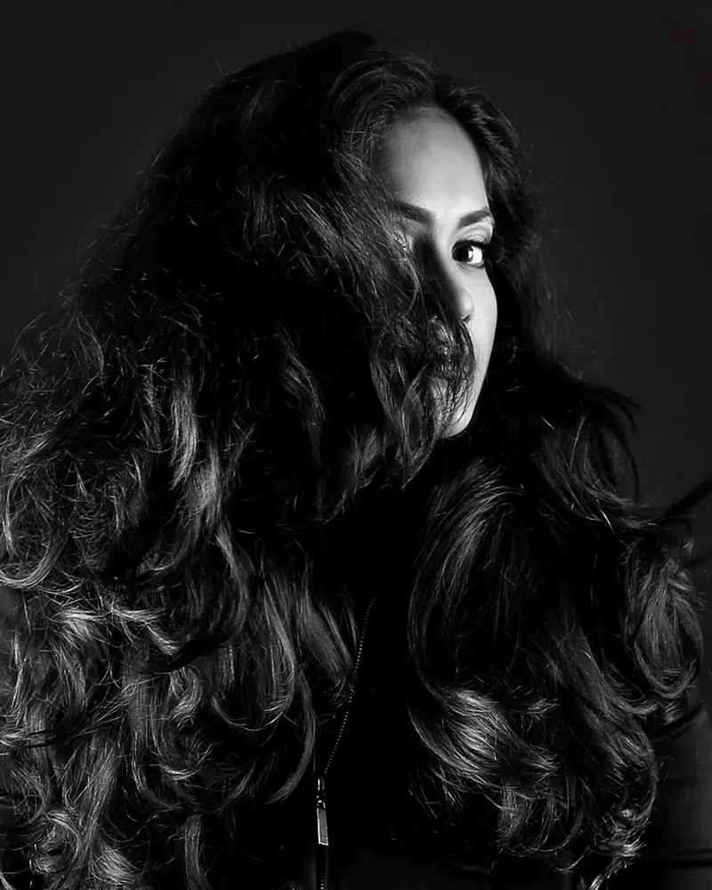 Striking black and white portrait showcasing long, wavy hair in a studio setting.