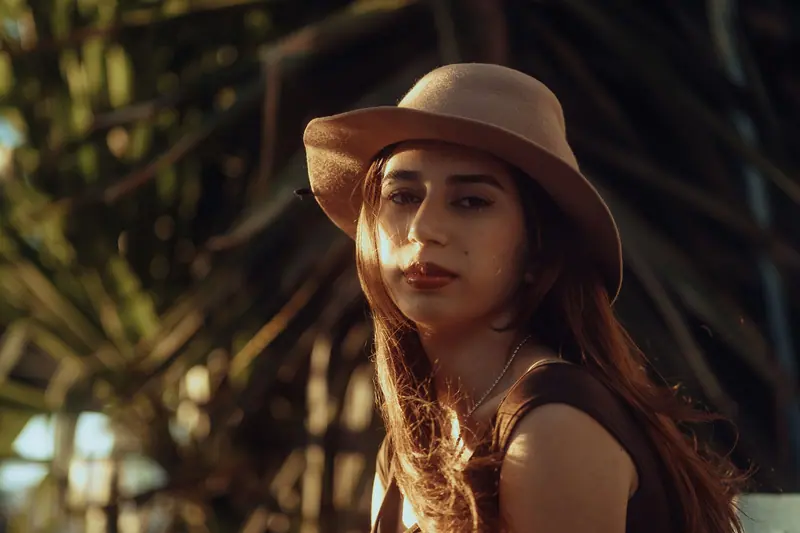 Portrait of a fashionable woman with a hat, captured in warm sunlight.