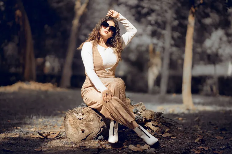 Fashionable woman with sunglasses posing in an autumn Indian forest.