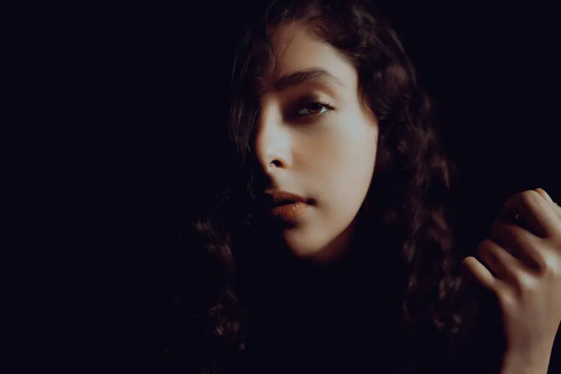 Dramatic portrait of a woman in chiaroscuro lighting with a mysterious expression.