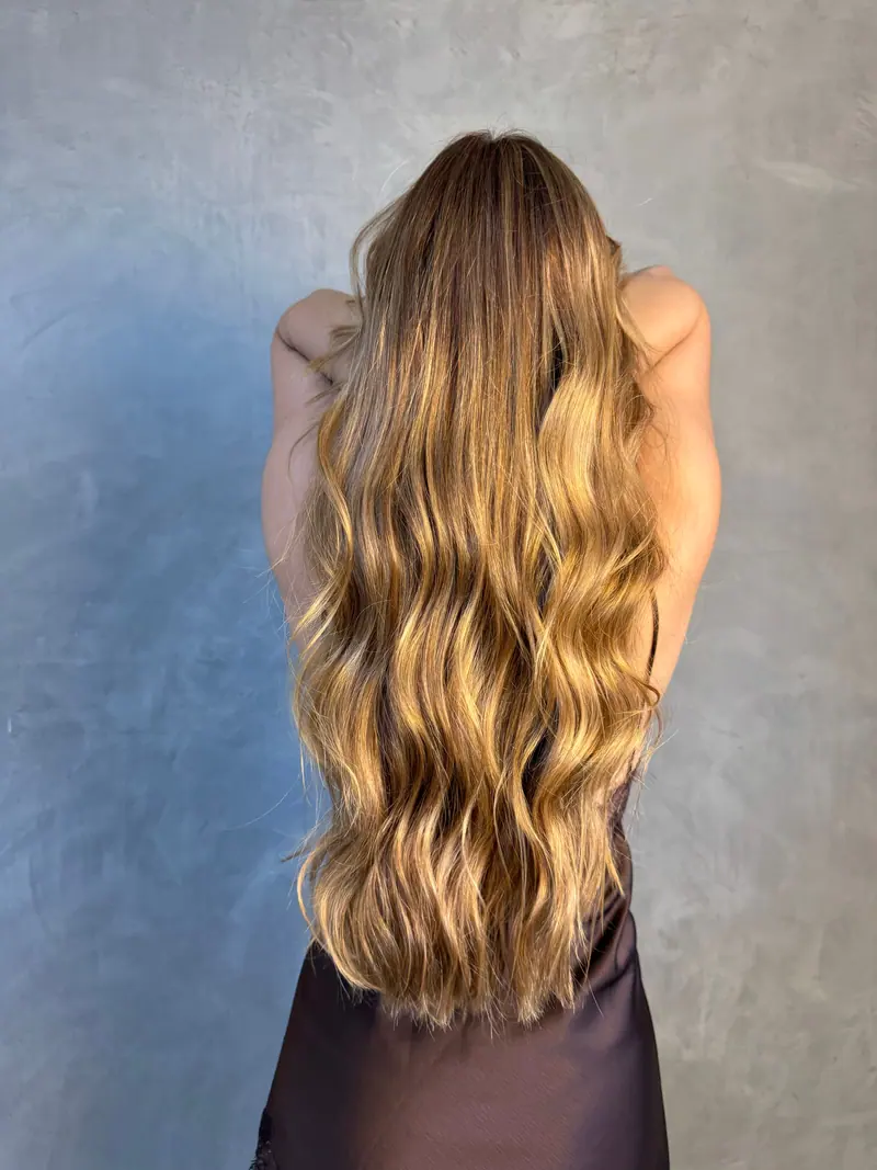 Model with flowing wavy blonde hair showcasing hairstyle in studio setting.