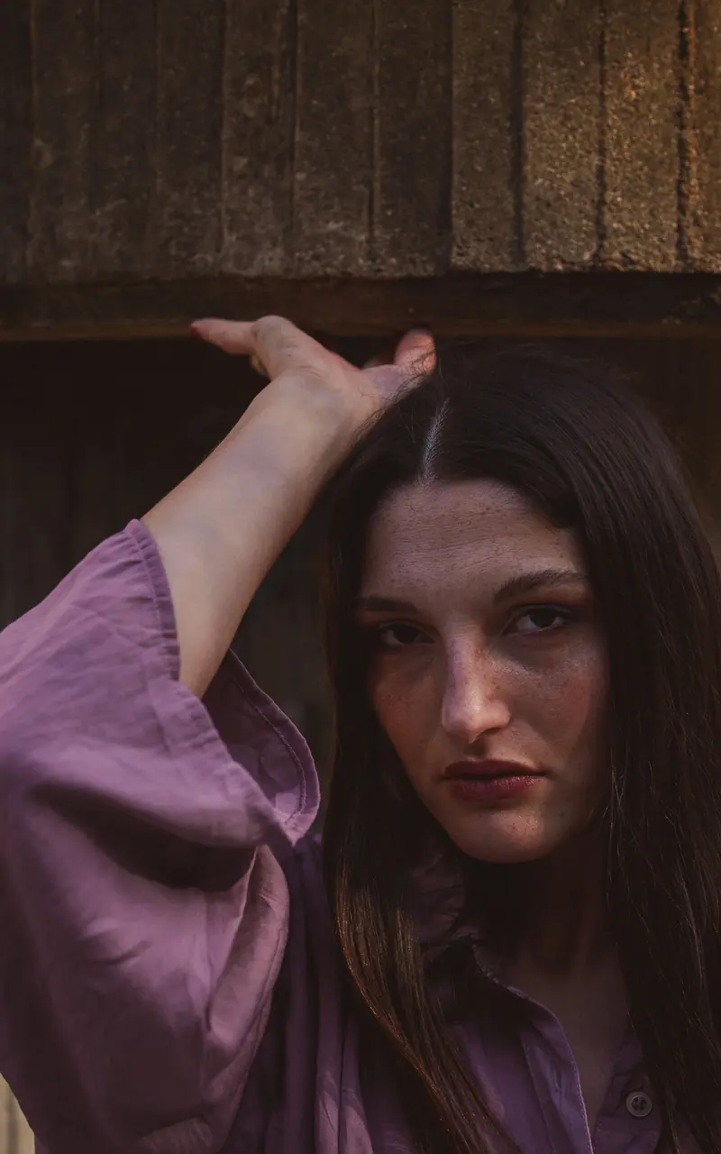 Portrait of a woman in a purple top with dramatic lighting and shadows.
