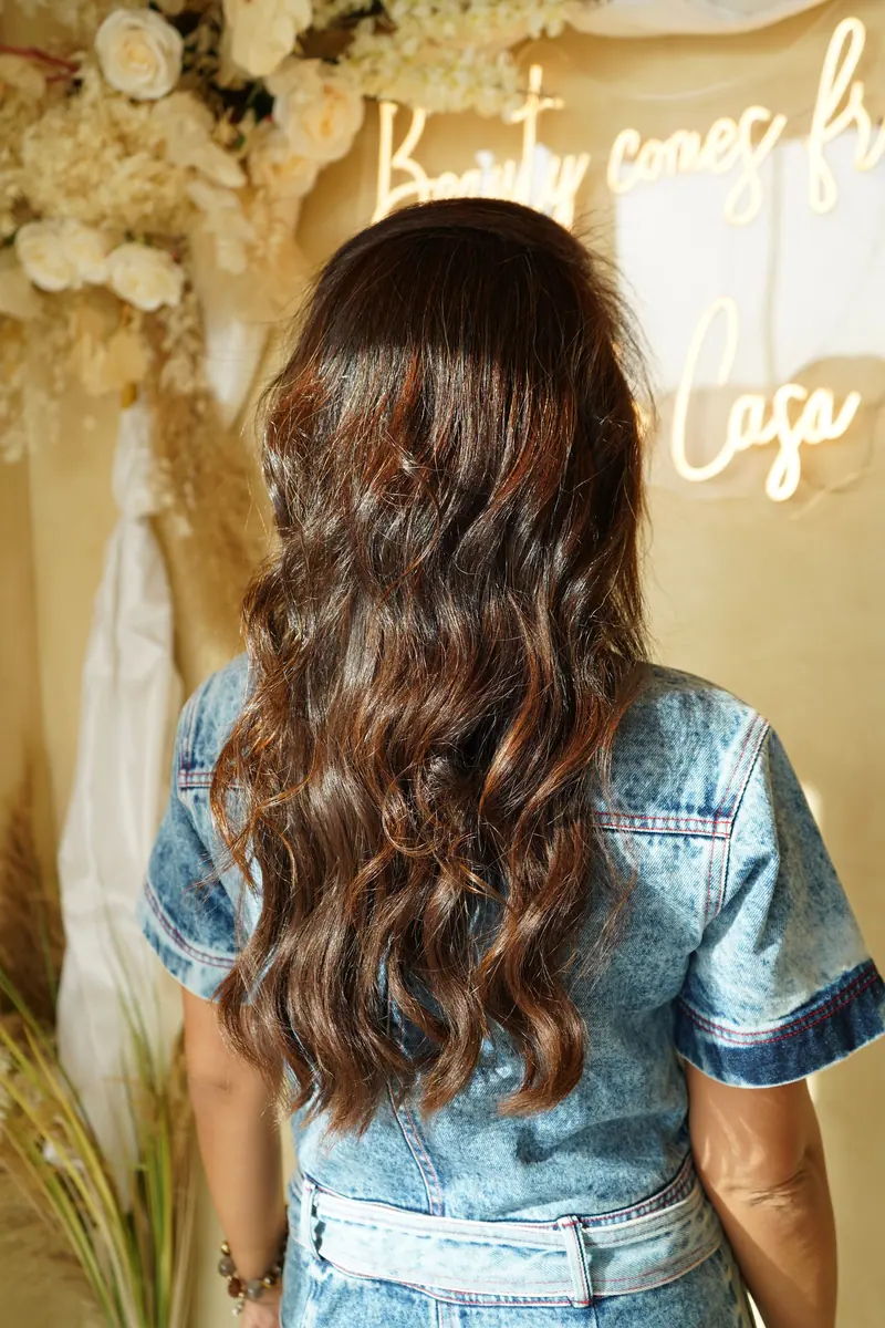 Back view of a brunette woman with wavy hair in a salon with floral decor in Dubai.