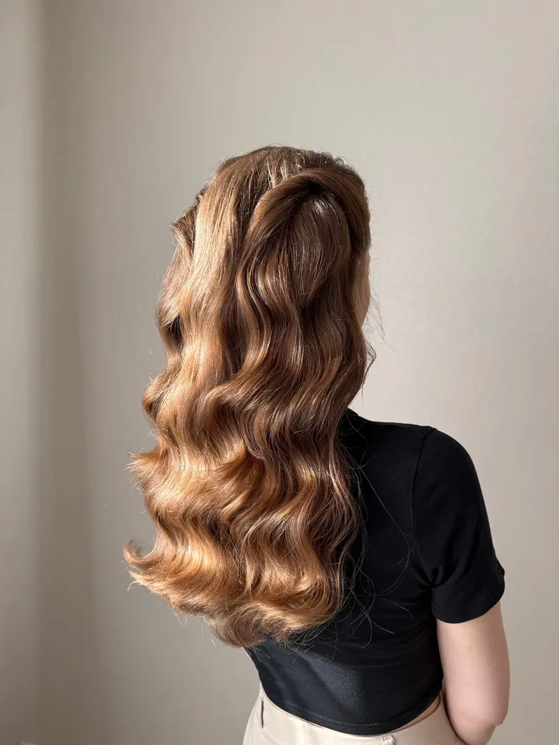 Back view of a woman with long wavy hair cascading down, illuminated by natural light.