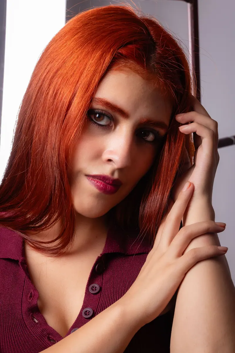 Close-up portrait of a woman with striking red hair and deep gaze, showcasing modern beauty.