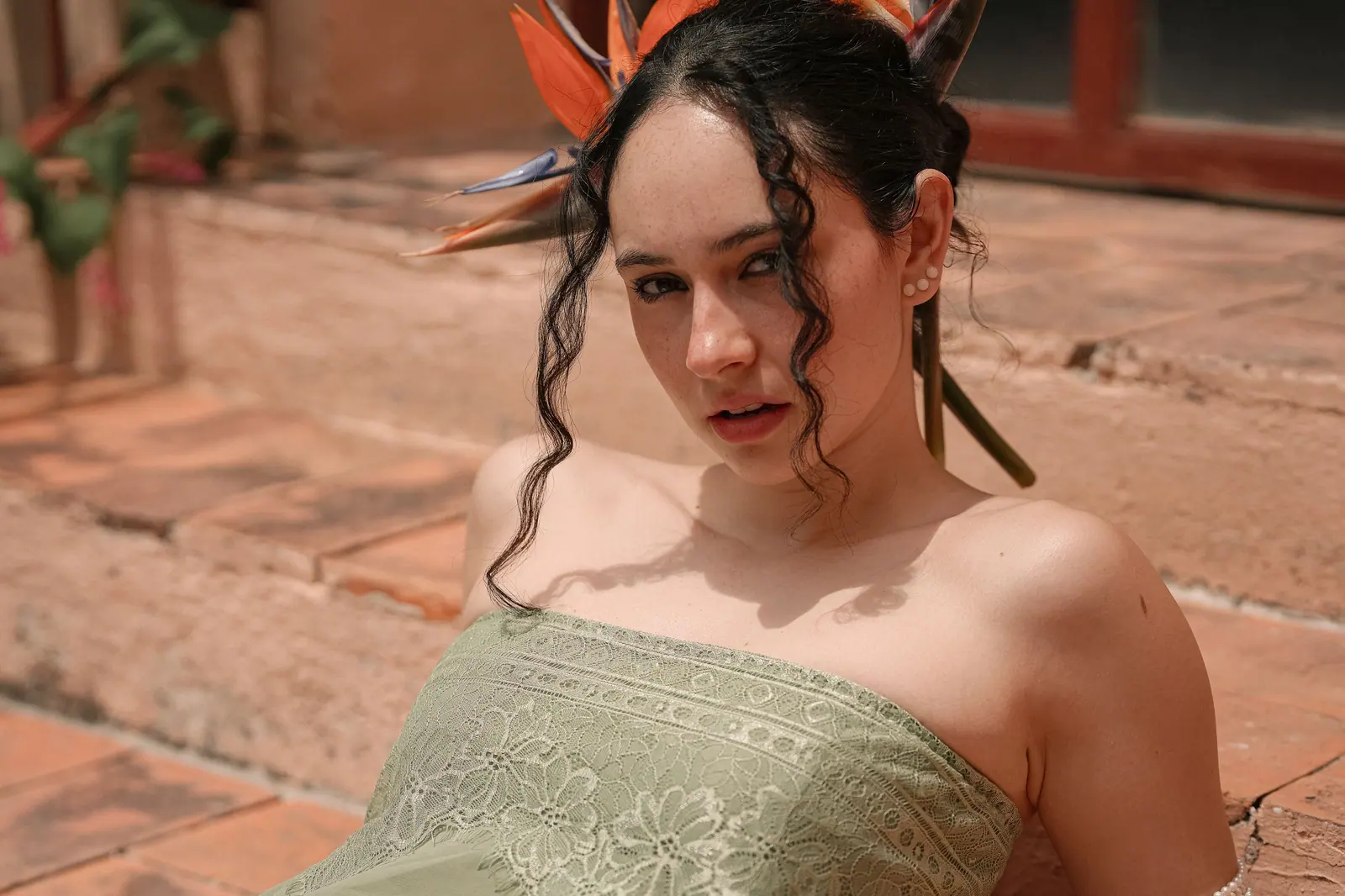 Portrait of a young woman in a strapless dress with a tropical flower in her hair, enjoying the sun.