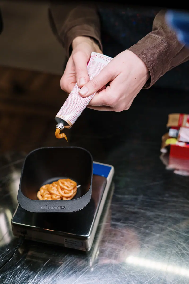 Close-up of hands squeezing hair dye into a bowl in a salon, showcasing a creative process.