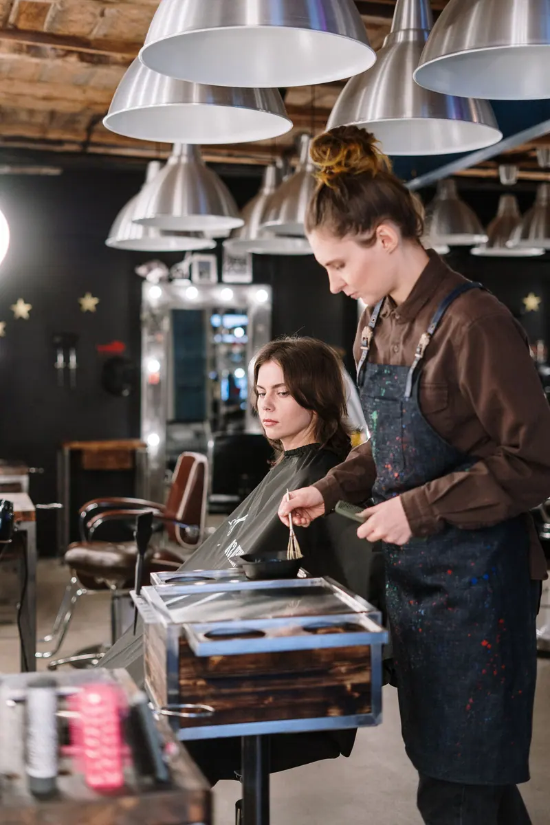 A hair stylist expertly colors a client's hair in a stylish salon setting.