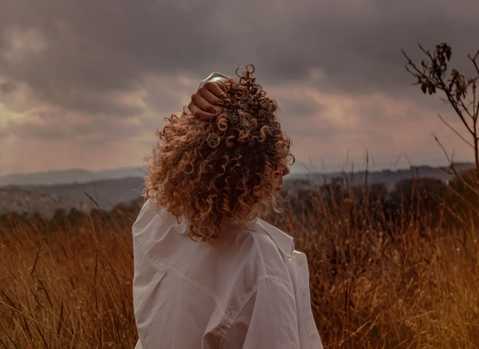 A woman enjoying a peaceful autumn evening in a scenic countryside field.