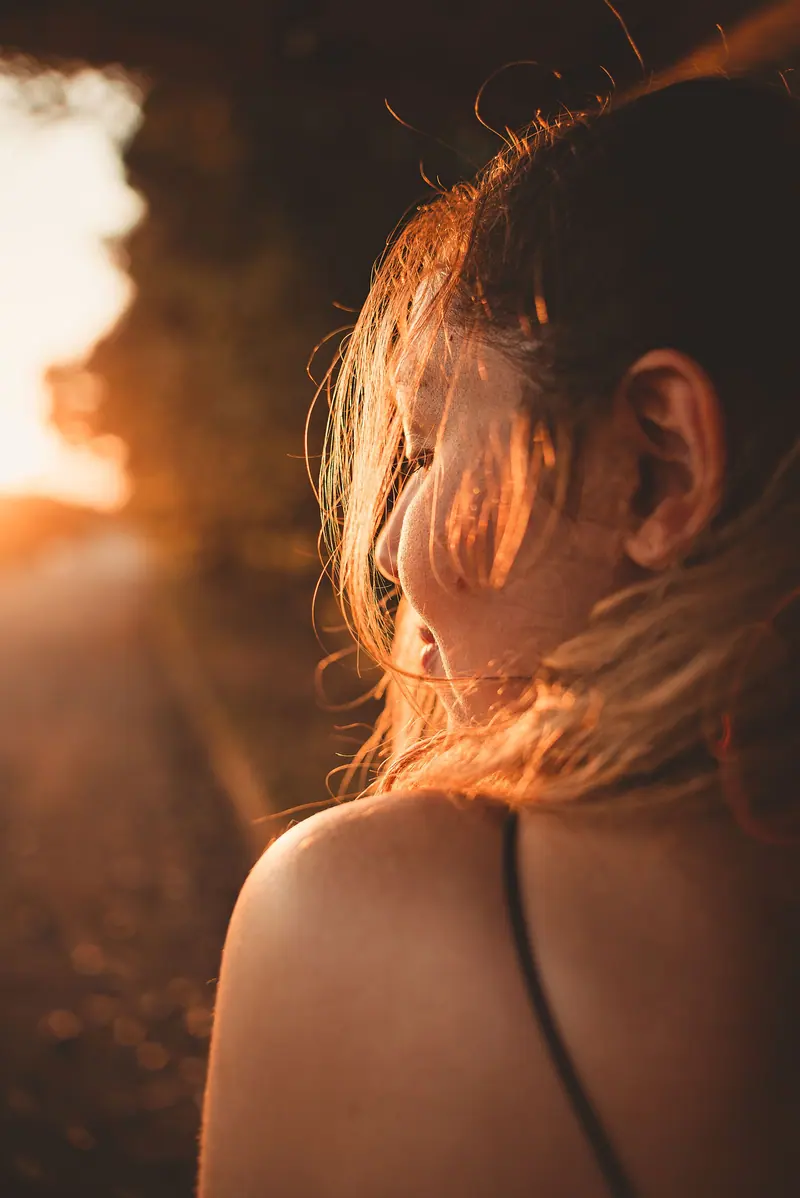 A serene moment captured during sunset, highlighting long hair and warm sunrays.