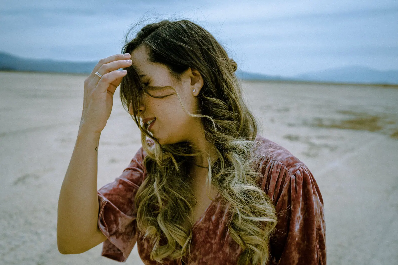 A stylish woman in a velvet outfit standing in a windy desert scene.