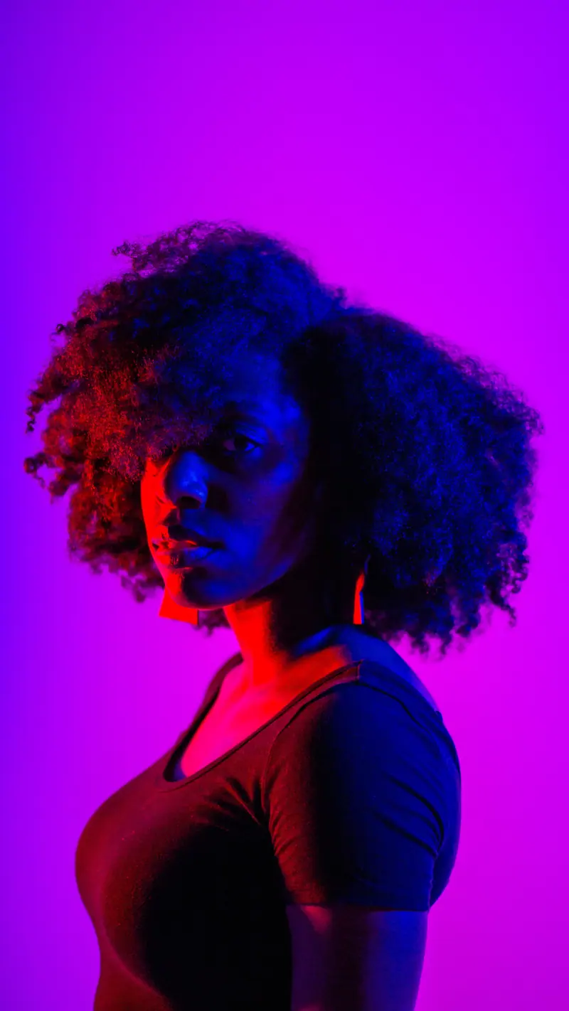 Striking portrait of a black woman with afro hair against a purple background.