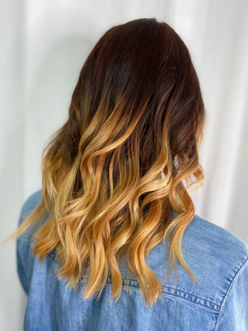 A woman showcasing beautiful ombre curly hair wearing a denim jacket.
