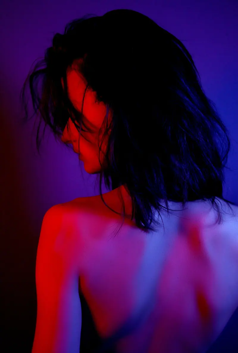 A captivating portrait of a woman with black hair in neon red and purple lighting, showcasing modern beauty.