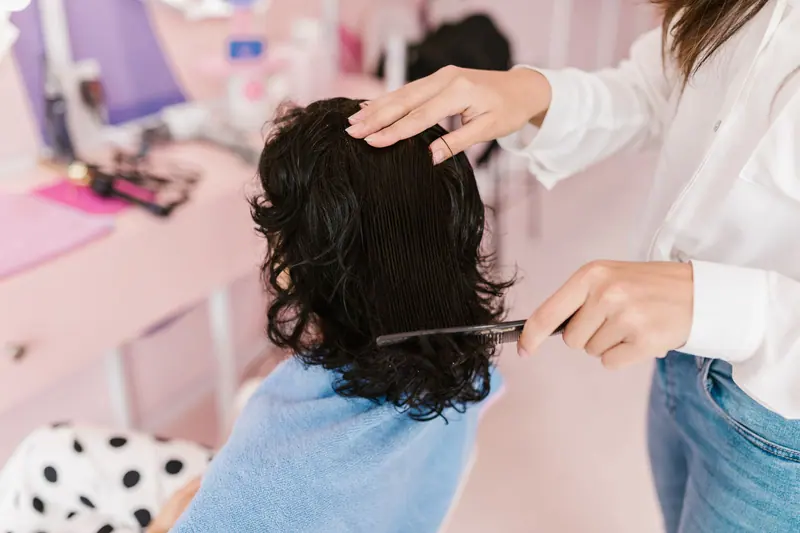 Close-up of a woman receiving hairstyling treatment in a contemporary salon.