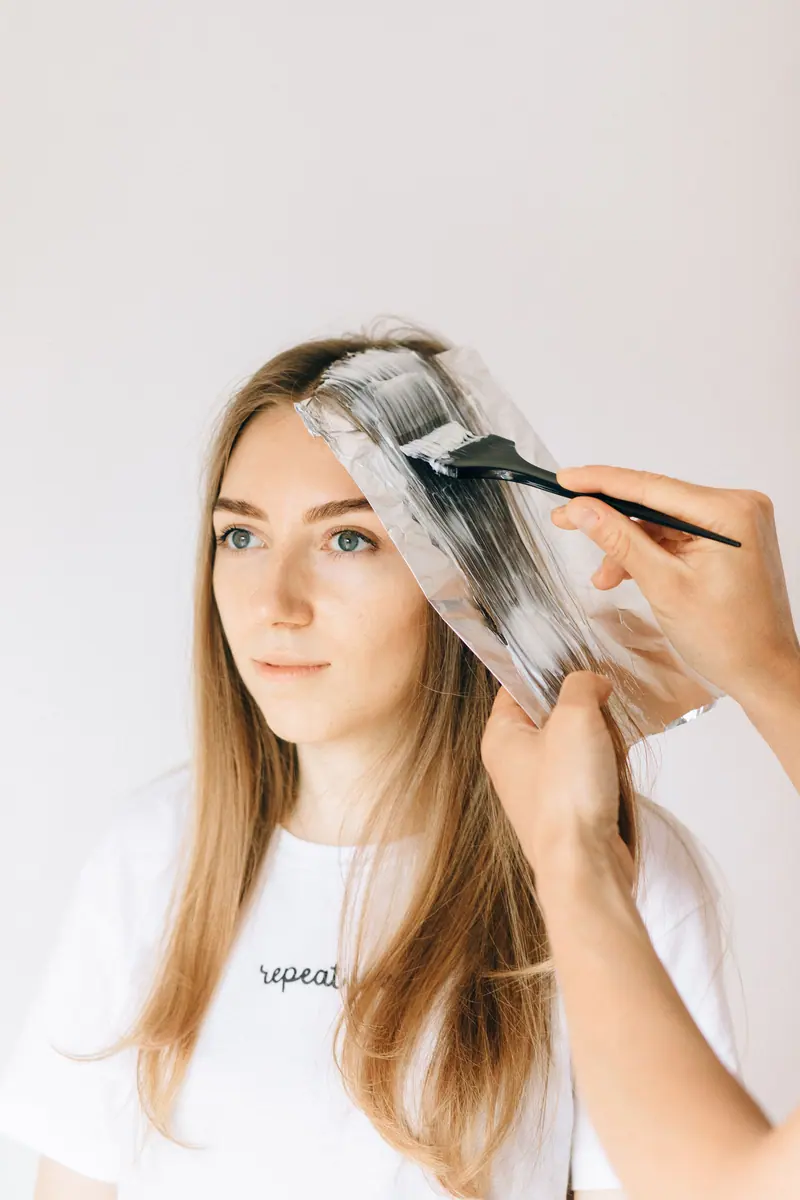 Colorist painting a balayage section on blonde hair