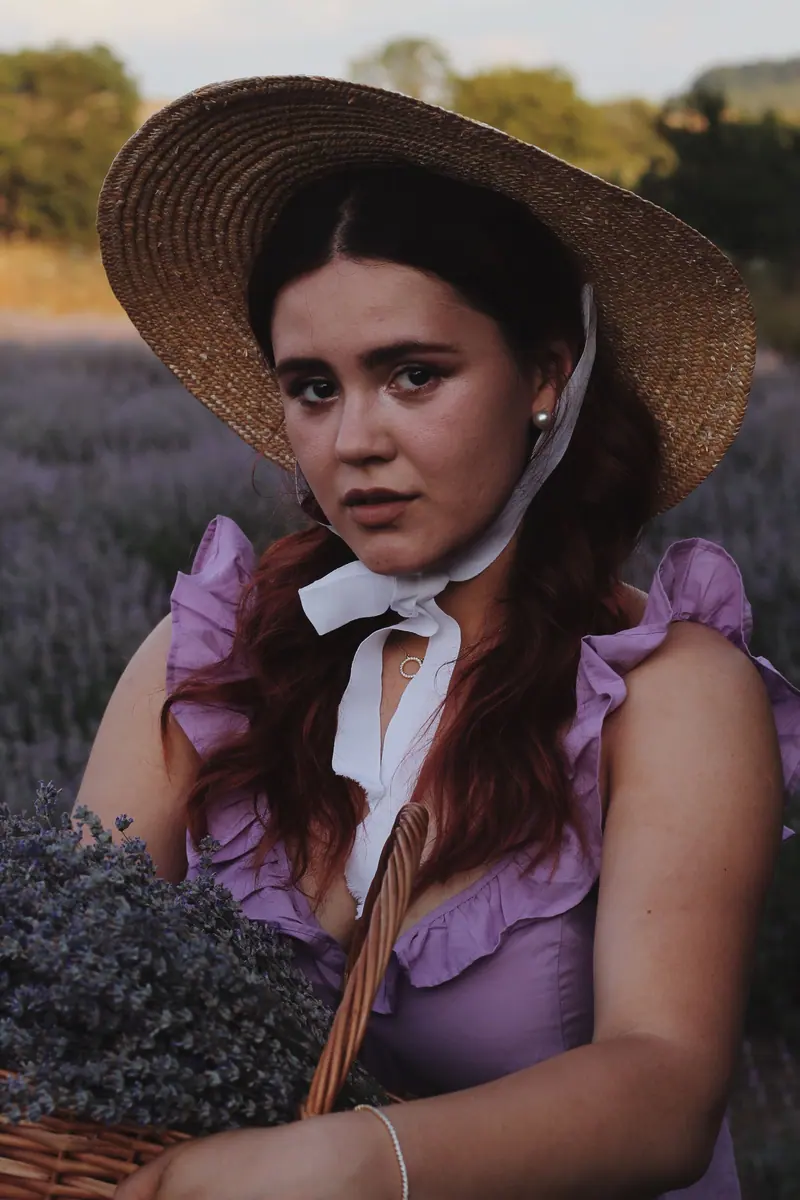 Woman in a sun hat holding lavender basket, capturing the essence of summer outdoors.