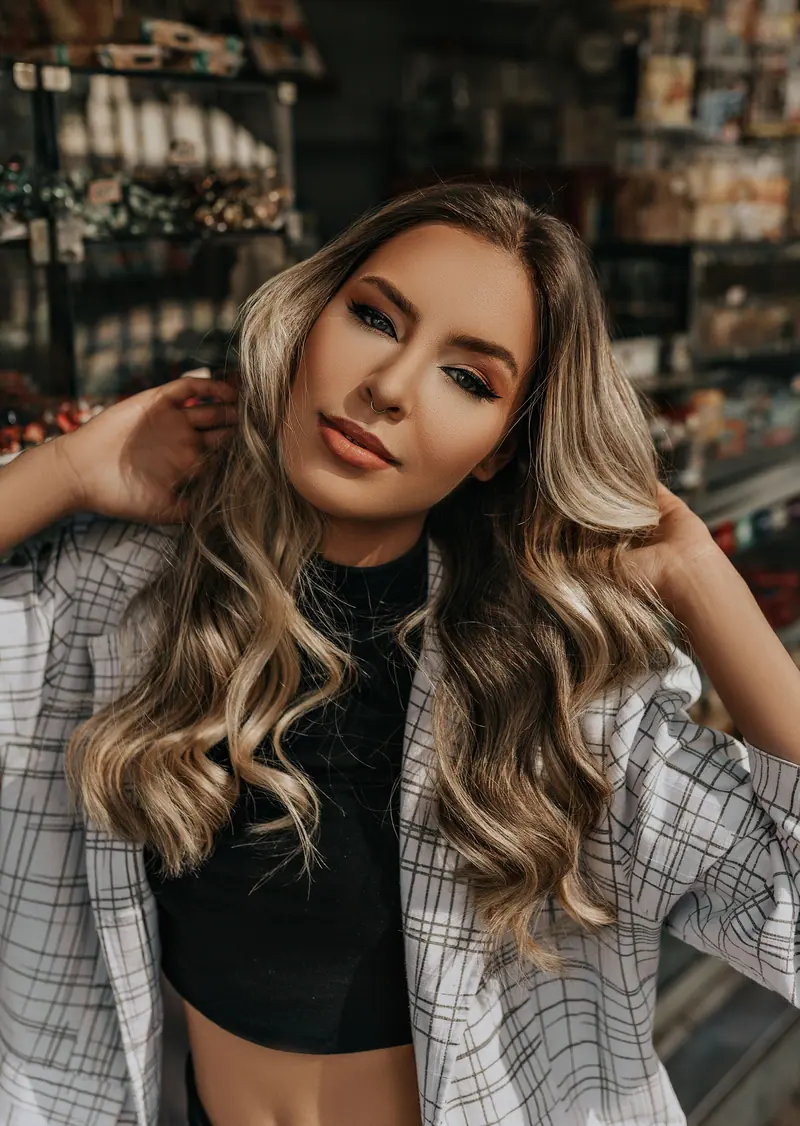 Close-up portrait of a beautiful woman in a plaid jacket with long blonde hair indoors.