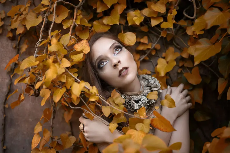 Enchanting portrait of a woman surrounded by golden autumn leaves in Portugal.