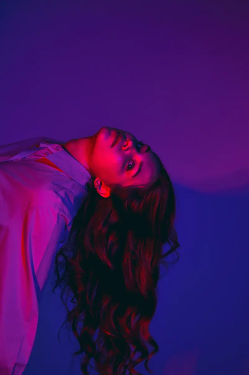 Captivating portrait of a woman with wavy hair in vibrant neon lighting creating an artistic mood.