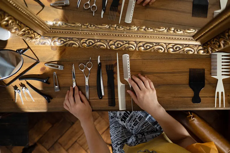 Overhead view of hair styling tools on wooden table next to a mirror.